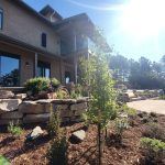 Contemporary two-story house with large windows and a layered rock garden in the foreground on a sunny day.