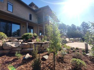Contemporary two-story house with large windows and a layered rock garden in the foreground on a sunny day.