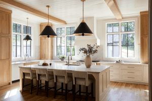 Bright kitchen with white cabinets, marble island, and black cone pendant lights hanging over a large island.