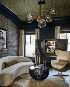 Cream curved sofa and matching ottoman sit on a light fur rug in a stylish living room with a black round coffee table and glassware.